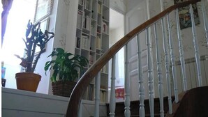 A staircase with white balusters leading to a landing with a bookshelf and a potted plant. - Biarritz St Charles. Quiet garden, Walking distance to beaches and golf course (Biarritz)