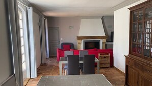 Una sala de estar con chimenea, un comedor con muebles rojos y un aparador con puertas de vidrio.