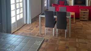 Amplia sala de estar con chimenea, comedor con mesa y sillas, y un ventanal con cortinas.