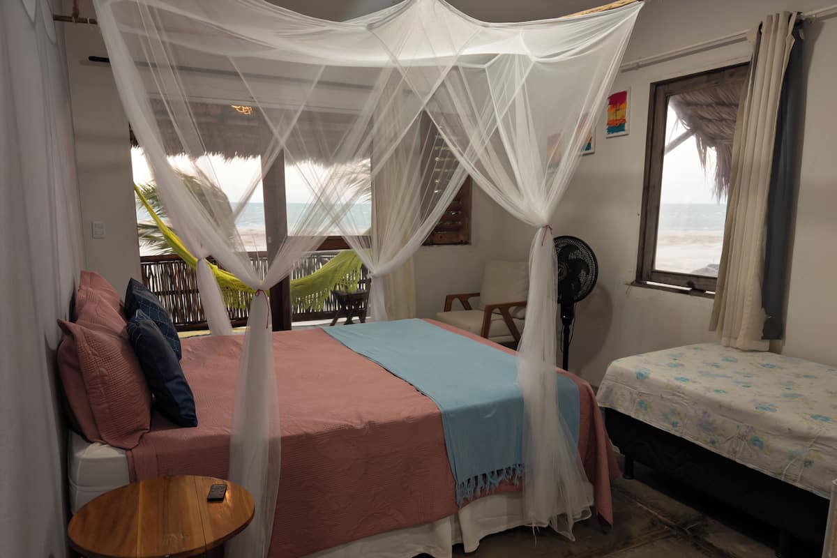 Ein Schlafzimmer mit Bett, Nachttisch und Blick auf den Ozean.