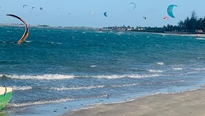 Una playa con varios cometas volando sobre el agua.