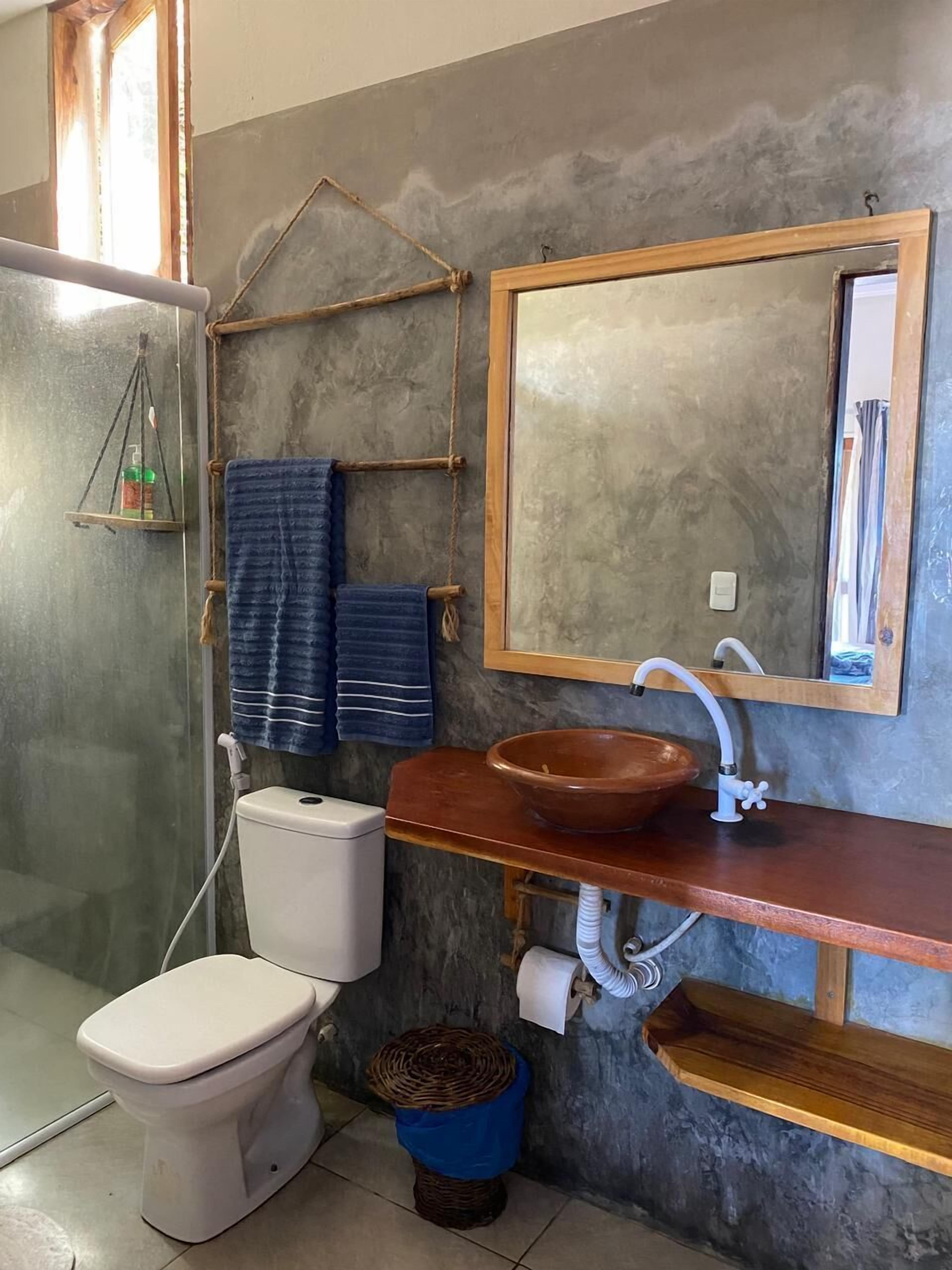 Un baño con inodoro, lavamanos con encimera de madera, espejo y barra para toallas.