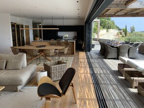 A modern living area with a dining table, sofas, and wicker furniture.