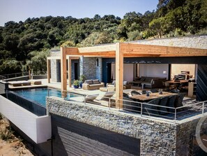 Una casa moderna con piscina, mobiliario exterior y fachada de piedra.