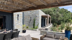 An outdoor patio with wicker furniture, stone walls, and a wooden pergola. - porto vechio saint cyprien (zonza)