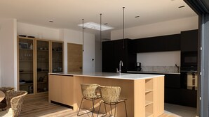 A modern kitchen with a central island, wooden cabinets, and a dining area with wicker chairs. - porto vechio saint cyprien (zonza)