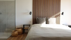 A modern bedroom with a large bed, a wooden slat wall, and two wall-mounted lamps. - porto vechio saint cyprien (zonza)