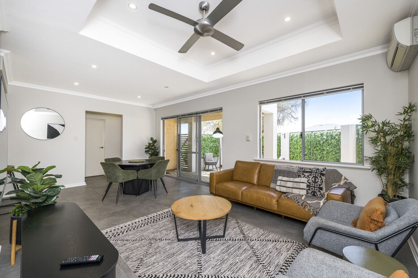 A modern living room with a ceiling fan, a sofa, a coffee table, and a dining area with chairs.
