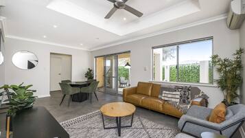 A modern living room with a ceiling fan, a sofa, a coffee table, and a dining area with chairs.