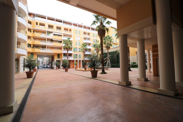 A spacious courtyard with a central fountain, surrounded by potted plants and palm trees.