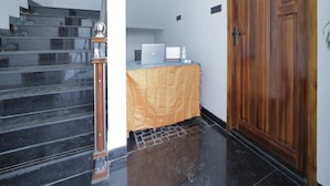 A staircase leading to a room with a wooden door, a laptop on a table, and a calendar on the wall. - APK Farm House (Noida)
