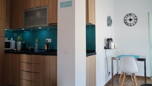 A modern kitchen with wooden cabinets, a built-in microwave, and a teal backsplash.