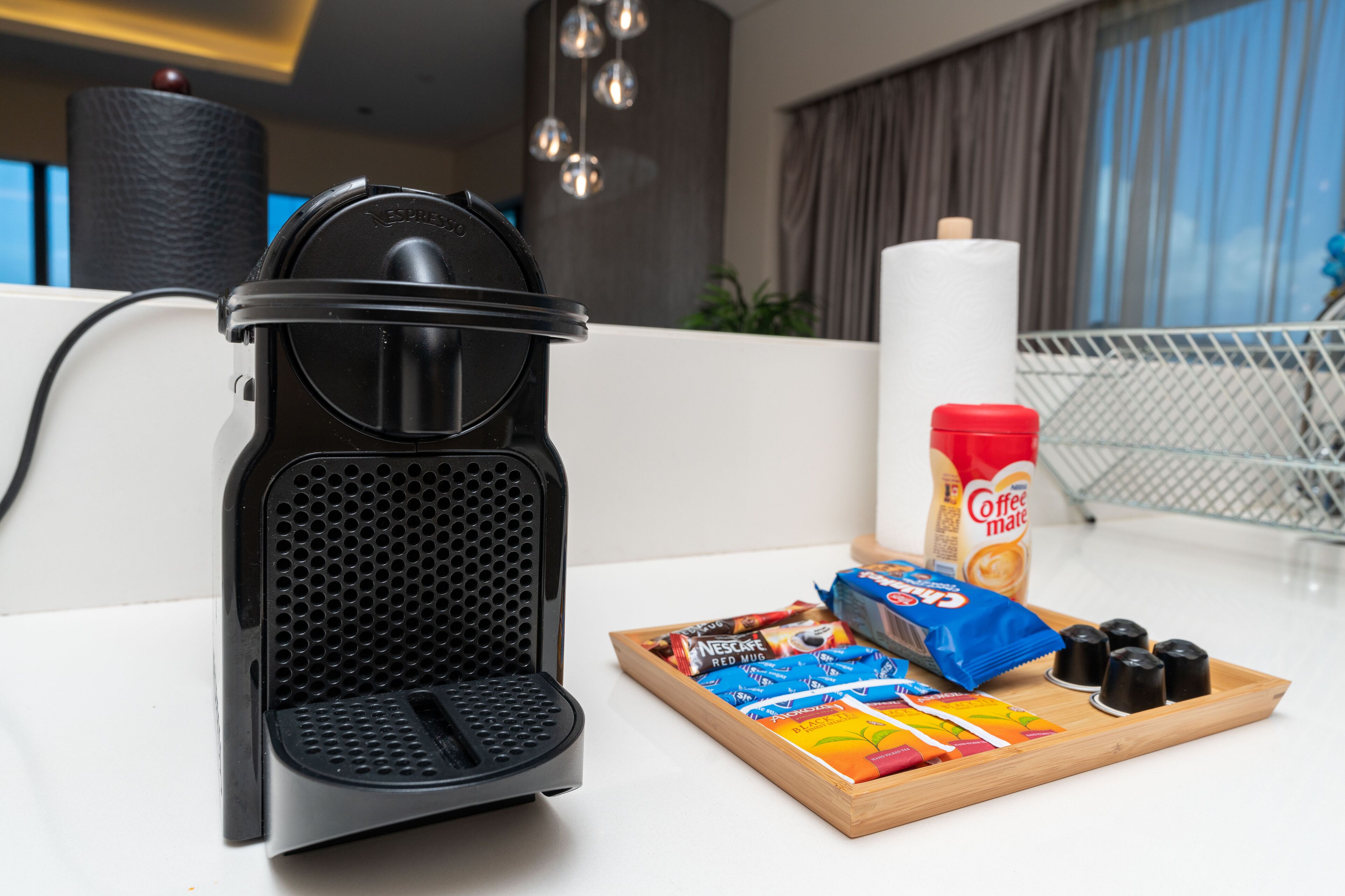 A coffee maker on a white countertop with a tray of coffee pods and a coffee mug.