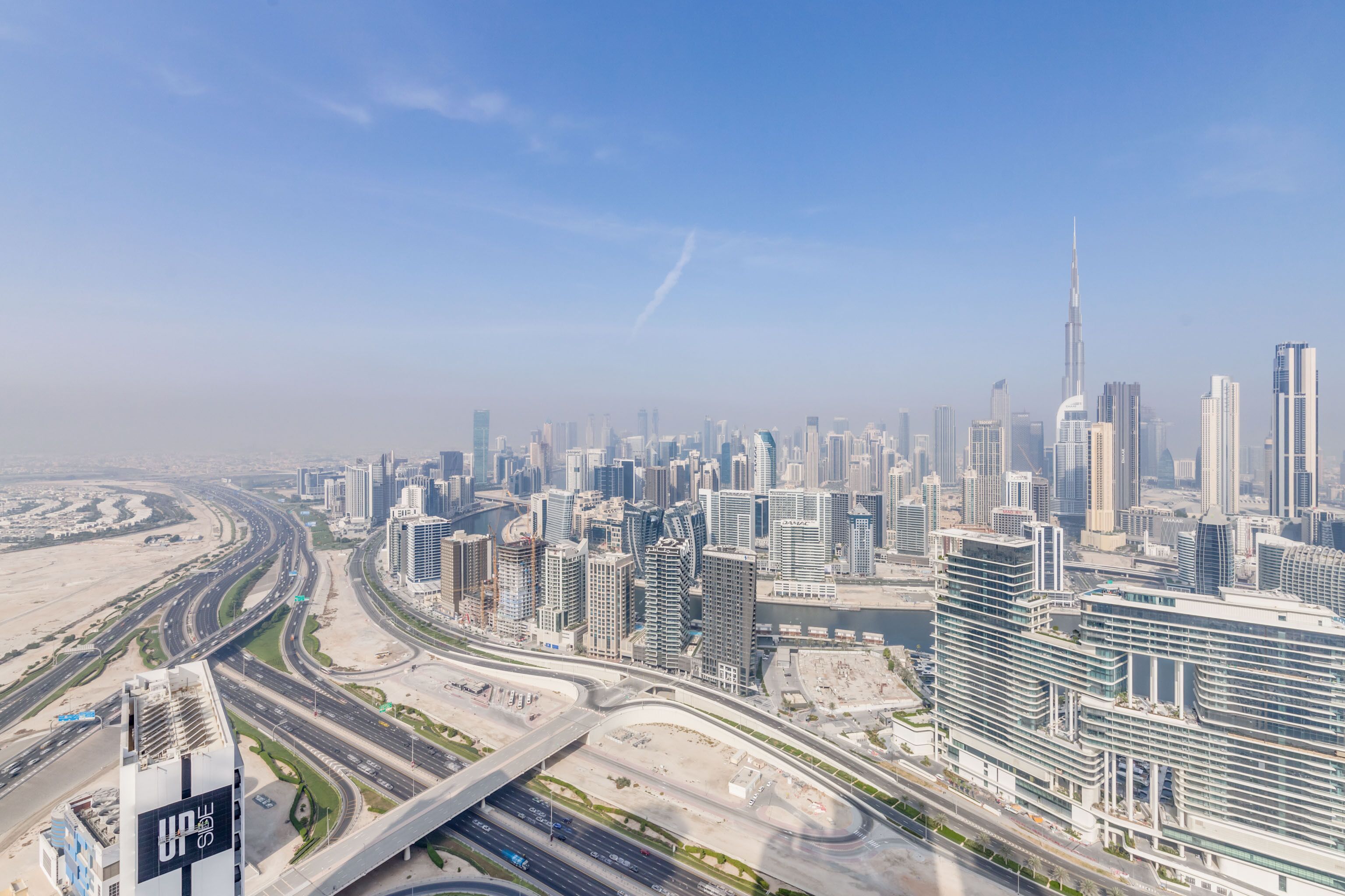 A cityscape with modern high-rise buildings, a prominent tower, and a complex highway interchange.