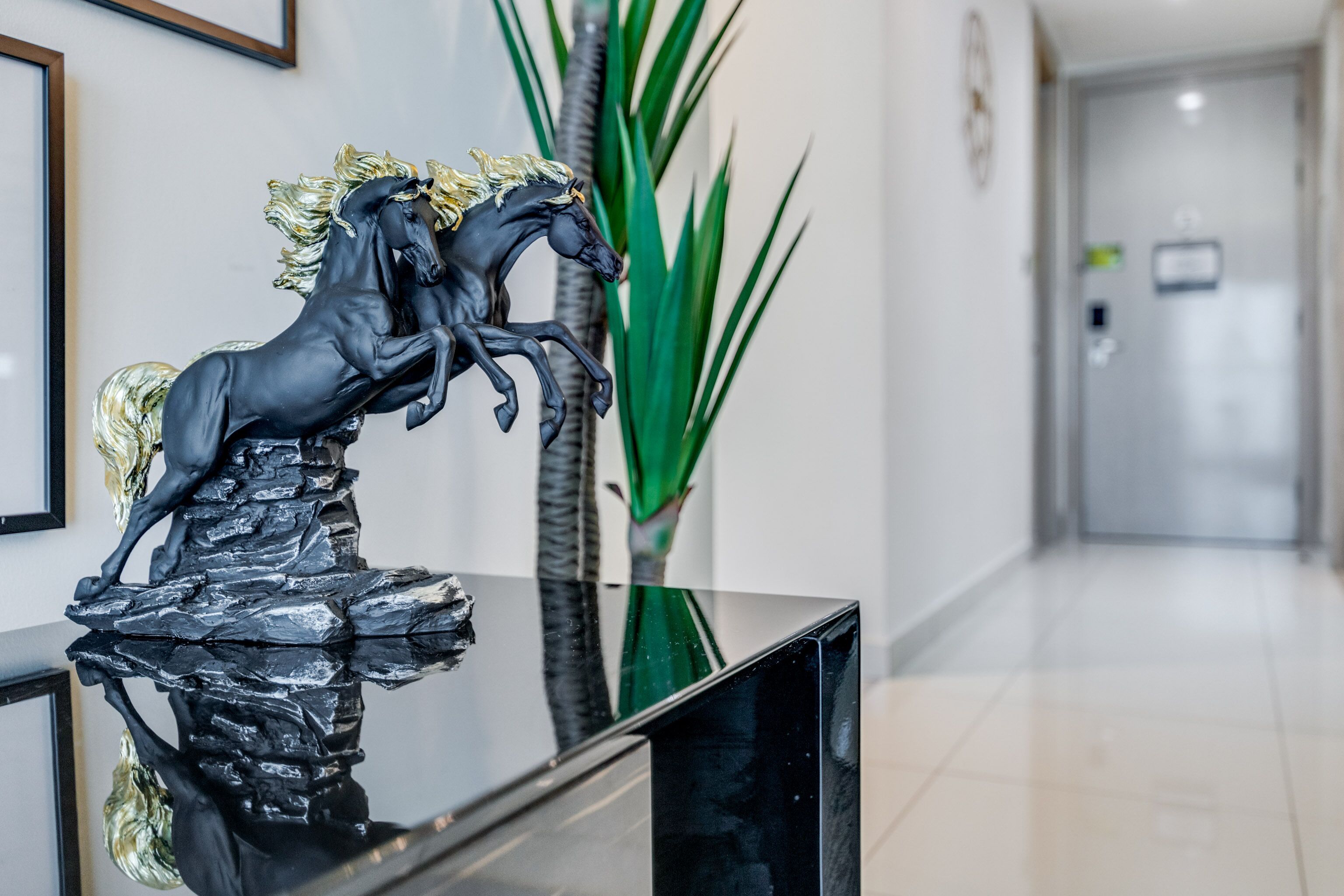 A reception area with a black marble reception desk, a black horse statue, and a tall green plant.