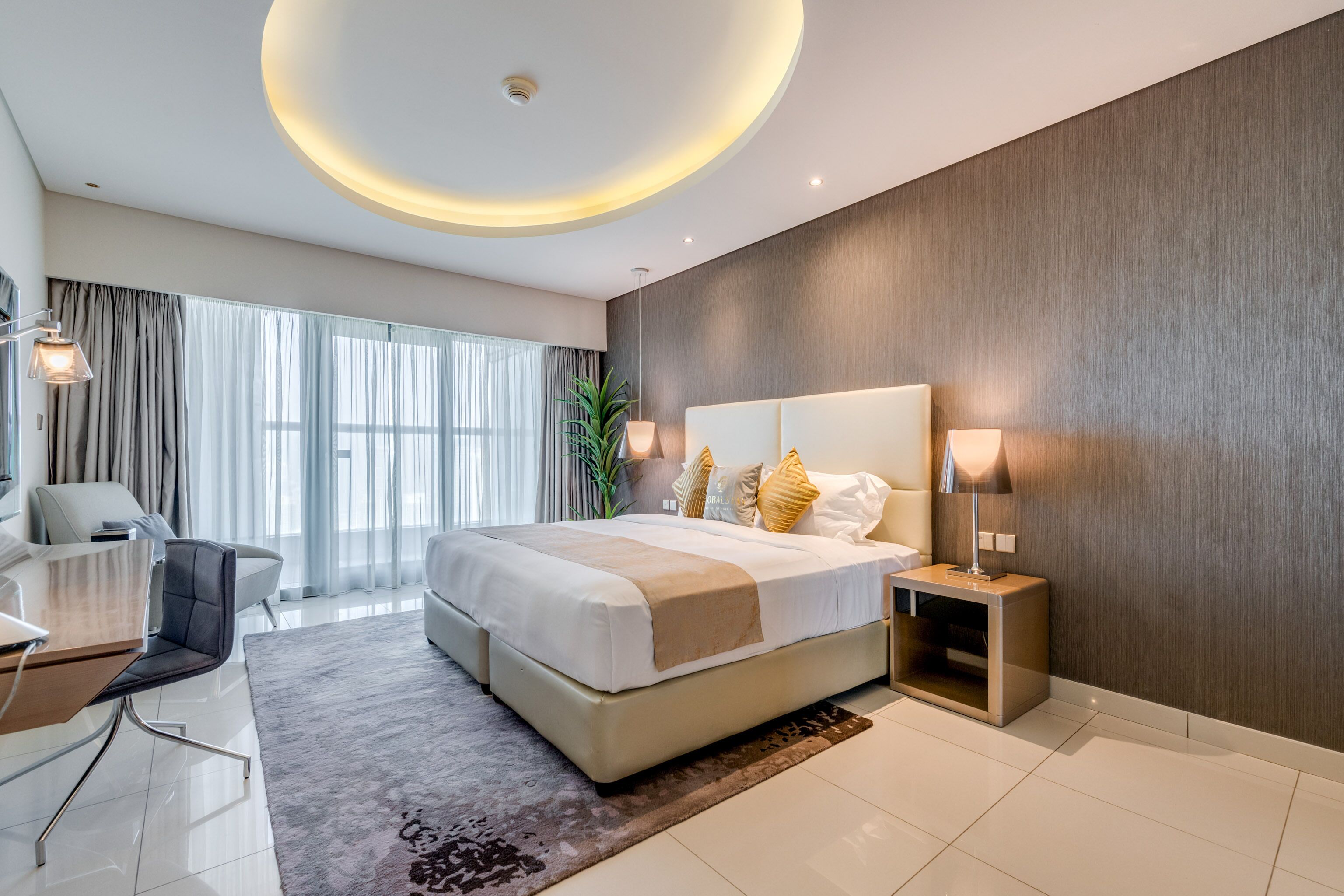 A modern hotel room with a large bed, bedside lamps, a desk, and a view of the outdoors.