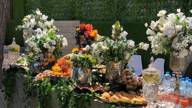 A buffet table with various food items, including fruits, vegetables, and bread, set up outdoors with a green hedge in the background. - The Friends Hotel (Yerevan)