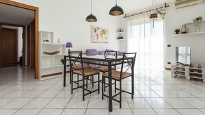 Ein moderner Essbereich mit einem Holztisch und Stühlen, einem weißen Regalschrank und einem großen Fenster mit Vorhängen.