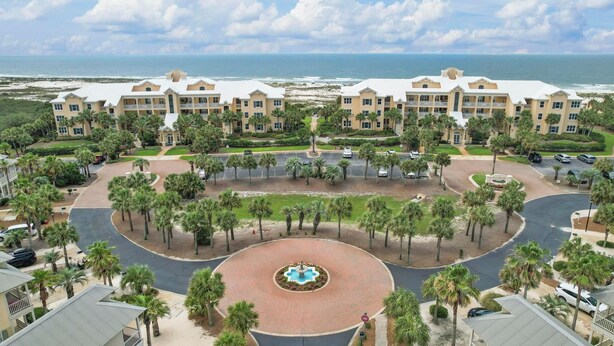 Un complejo turístico con varias edificaciones, una fuente central y vistas a la playa.