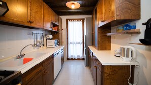 A narrow kitchen with wooden cabinets, a white countertop, and a built-in microwave. - Residenza Airone (Polpenazze del Garda)