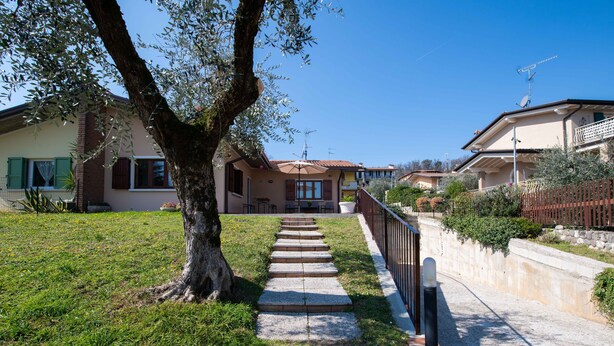 A residential street with a tree-lined pathway leading to houses with balconies. - Residenza Airone (Polpenazze del Garda)