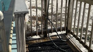 Una terraza de madera con barandilla de metal que da a una playa.