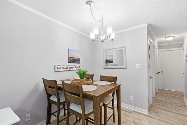 A dining area with a wooden table, chairs, a chandelier, and wall art.