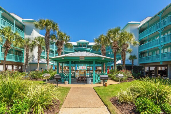 A resort with a central gazebo, palm trees, and a clear sky.