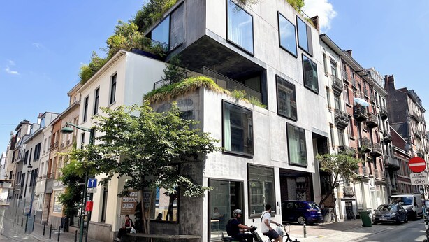 Un edificio moderno con amplias ventanas y un jardín en la azotea.