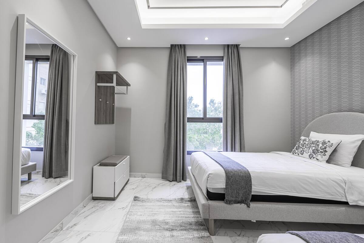 A modern bedroom with a skylight, a bed with a grey headboard, and a large mirror.