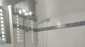 Une salle de bain avec un lavabo blanc, des meubles noirs, une douche en verre et une baignoire blanche.