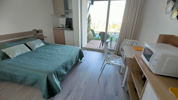Une chambre d’hôtel avec un lit, un bureau doté d’un micro-ondes, une chaise et une vue sur l’extérieur.