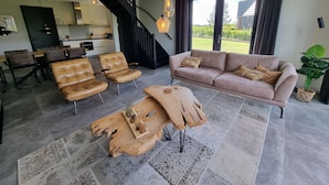 A modern living room with a sofa, two leather chairs, a coffee table, and a dining area with chairs and a table. - Water Villa in Balk by Slotermeer Lake (Balk)