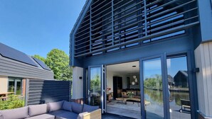 A modern house with a deck, a sofa, and a dining table. - Water Villa in Balk by Slotermeer Lake (Balk)