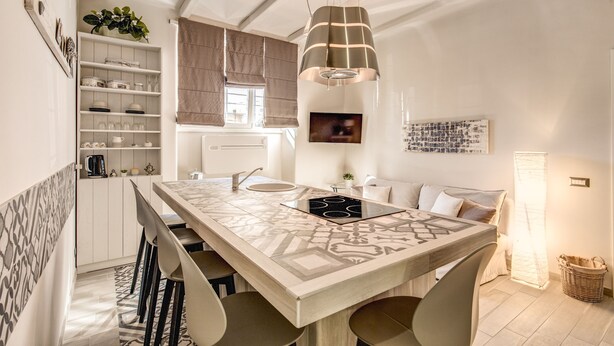 A modern kitchen with a central island, pendant lighting, and a dining area with bar stools.