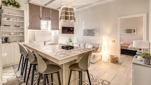 A modern kitchen with a central island, bar stools, and a hanging pendant light.