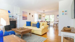 Una sala de estar con sofá, una mesa de centro y una chimenea. Hay un comedor con una mesa y sillas.