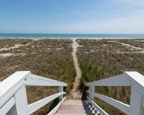 Una passerella di legno che conduce a una spiaggia con vista limpida sull'oceano.