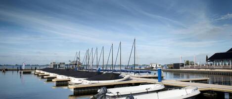 A marina with several boats docked, a control building, and a clear sky.