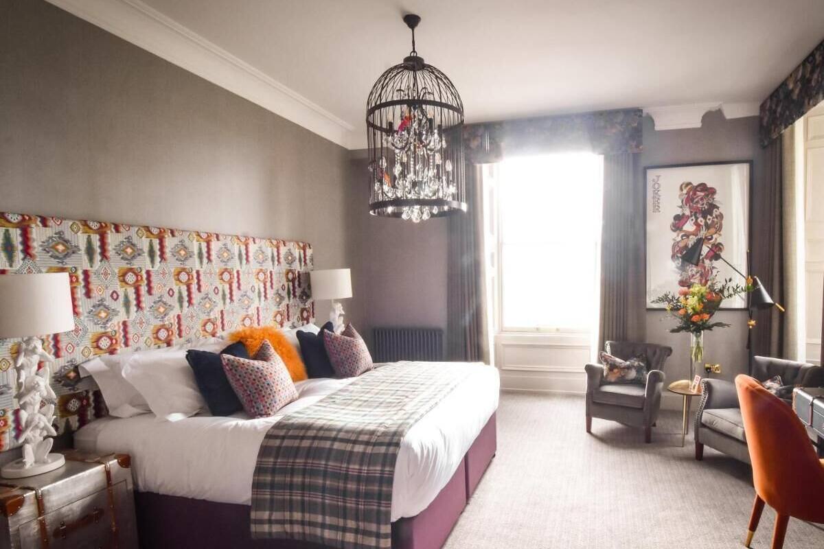 Un dormitorio con cama, candelabro, silla, escritorio y ventana.