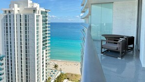 A balcony with a view of the ocean and a beach, overlooking a tall hotel building. - Cozy unit @ 18th Floor with Ocean view (Hollywood)
