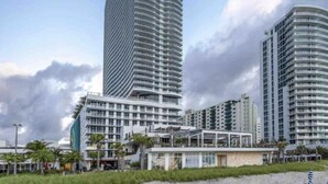 A modern high-rise hotel with a curved facade, multiple balconies, and a beachfront location. - Cozy unit @ 18th Floor with Ocean view (Hollywood)