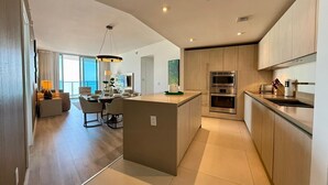 A modern kitchen with a central island, built-in ovens, and a dining area with a view. - Cozy unit @ 18th Floor with Ocean view (Hollywood)