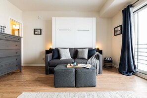 Un salon moderne avec un canapé, un pouf et une commode.