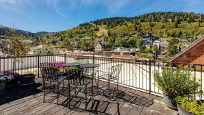 Eine Terrasse mit Sitzgelegenheiten, Blick auf ein malerisches Haufendorf und einen klaren Himmel.