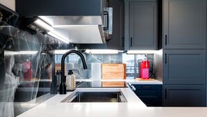 Eine moderne Küche mit Spüle aus Edelstahl, einem schwarzen Wasserhahn und einer Holz-Schneidebrett auf der Arbeitsplatte.