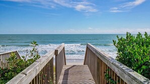 Une promenade en bois menant à une plage avec vue sur l’océan.