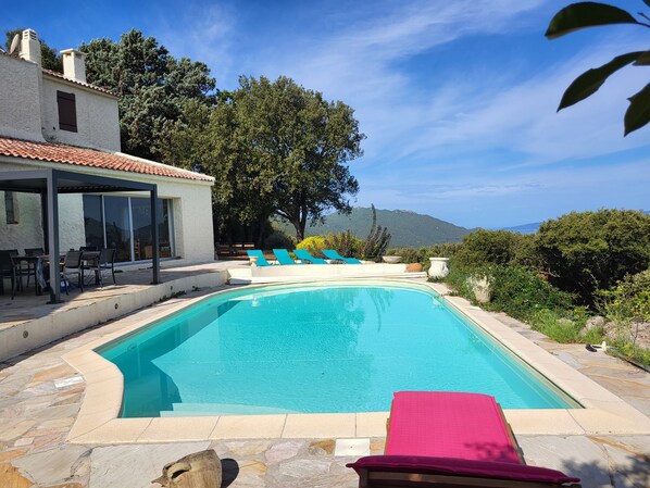 A swimming pool with lounge chairs and a covered patio area.