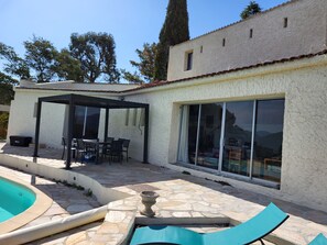A house with a patio, a swimming pool, and a covered outdoor dining area.