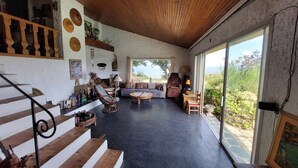 Un espacio habitable amplio con una escalera de madera, un conjunto de sofás, una mesa redonda y vistas al exterior a través de ventanas grandes.